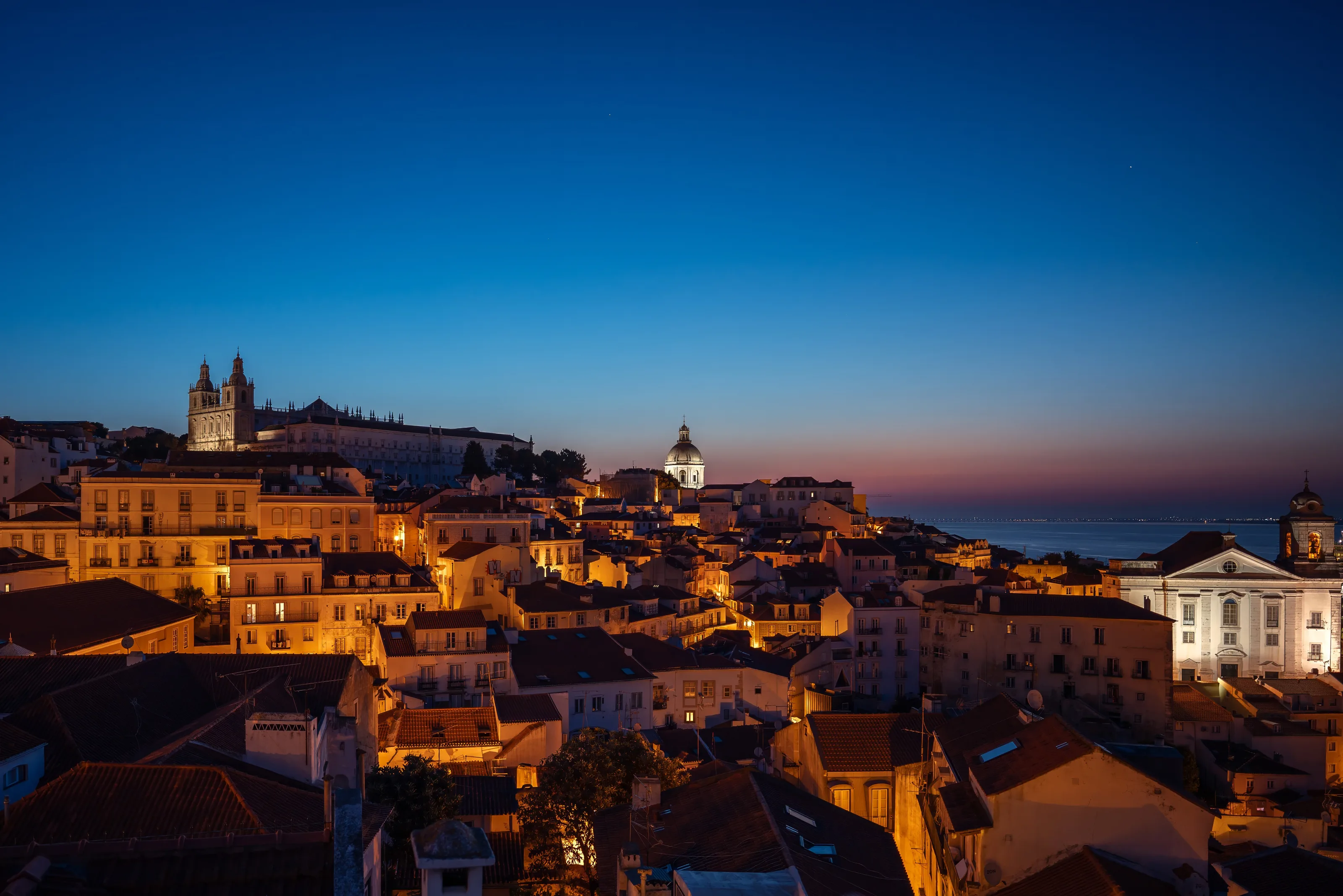 The terracotta rooftops of Alfama glow in the last light of a Lisbon evening — the city's oldest neighbourhood, draped in golden hour.