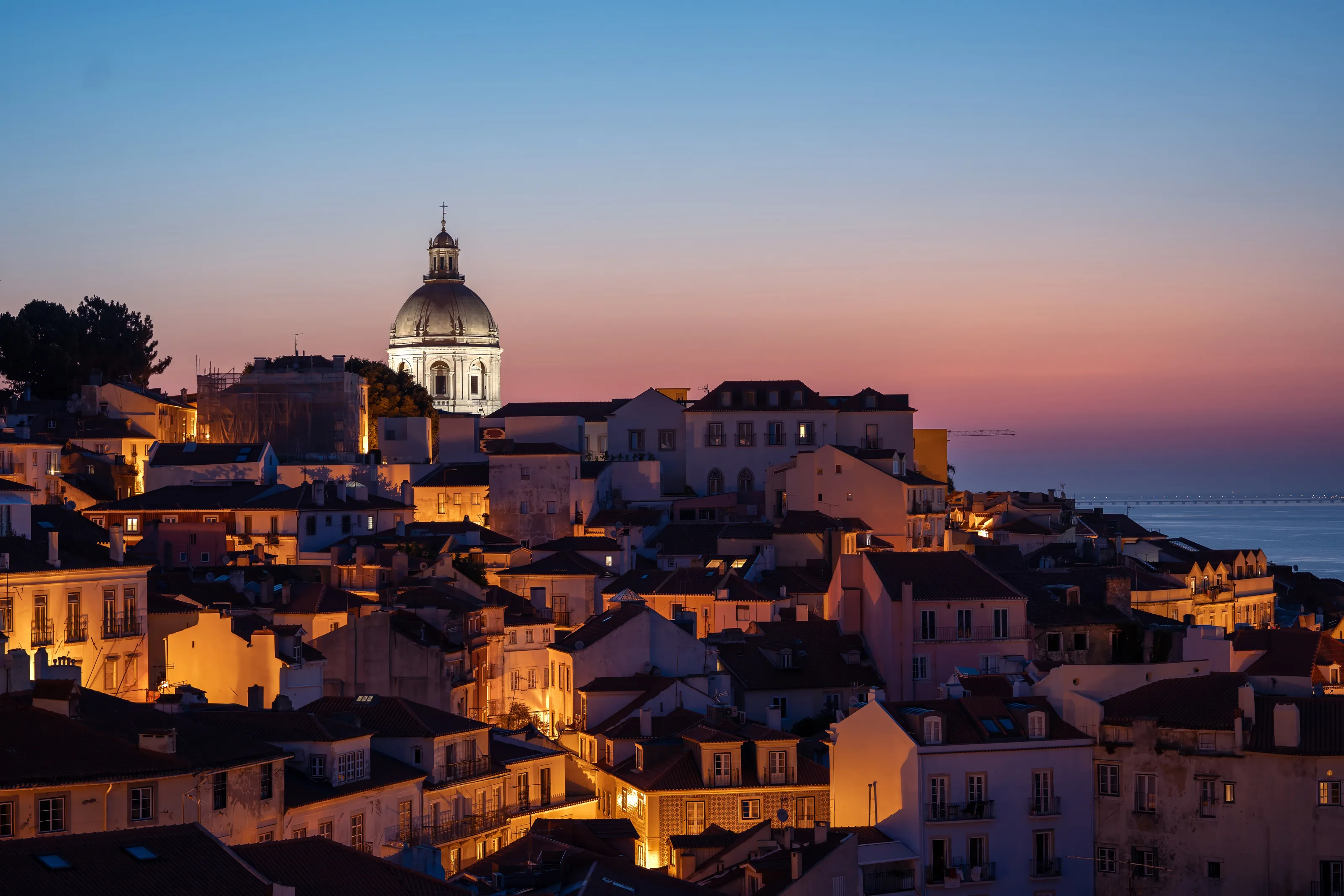The dome of the Church of Santa Engrácia rises above Lisbon at dusk — copper light, baroque grandeur, and the city humming below.